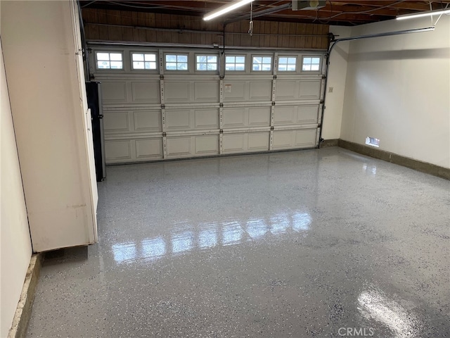 garage featuring baseboards and freestanding refrigerator