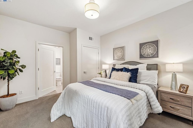 bedroom with ensuite bathroom and light carpet