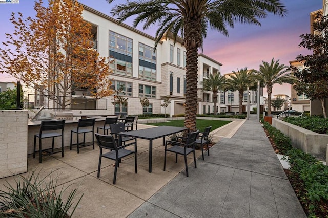 patio terrace at dusk featuring exterior kitchen and an outdoor bar