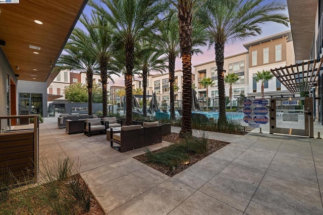 patio terrace at dusk with a community pool and an outdoor living space