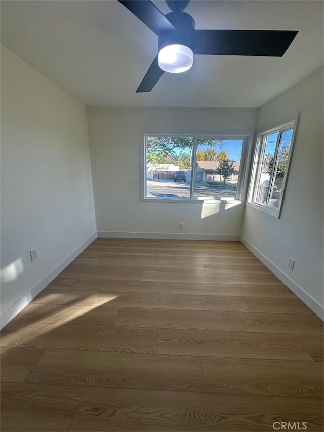 spare room featuring wood-type flooring, ceiling fan, and a healthy amount of sunlight