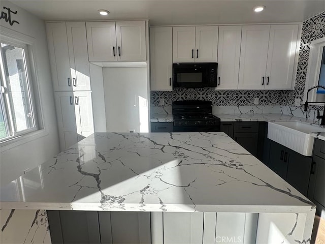 kitchen featuring white cabinets, sink, light stone counters, and black appliances