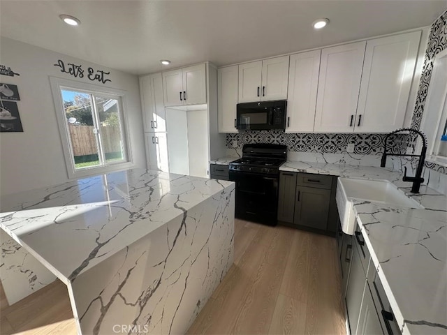 kitchen featuring black appliances, white cabinets, sink, light stone countertops, and light wood-type flooring