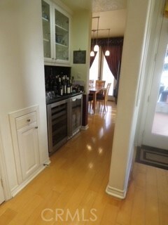 kitchen featuring wine cooler, white cabinets, decorative light fixtures, and light hardwood / wood-style floors