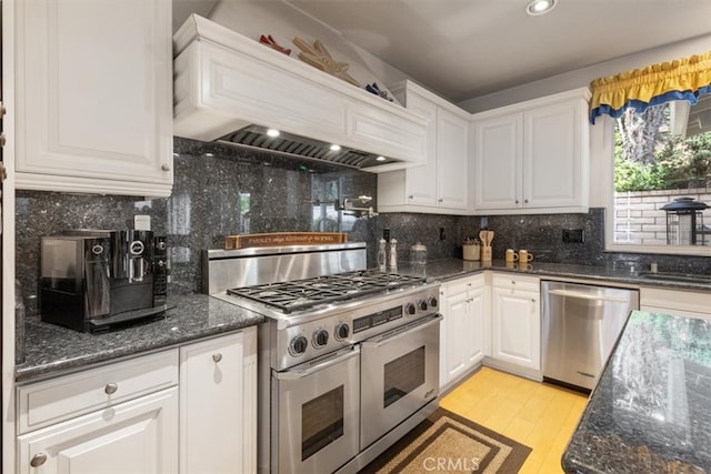 kitchen with custom exhaust hood, white cabinets, stainless steel appliances, and tasteful backsplash