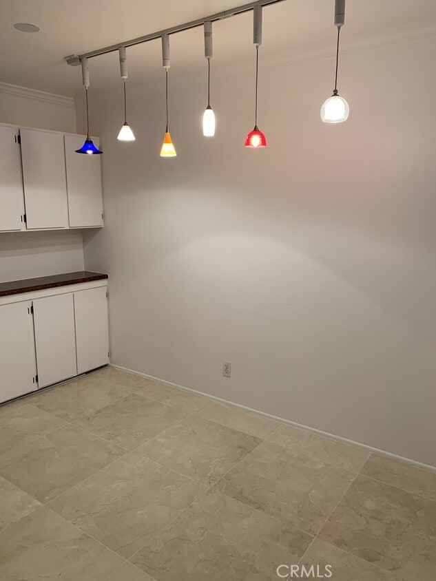 kitchen with pendant lighting, white cabinetry, and crown molding