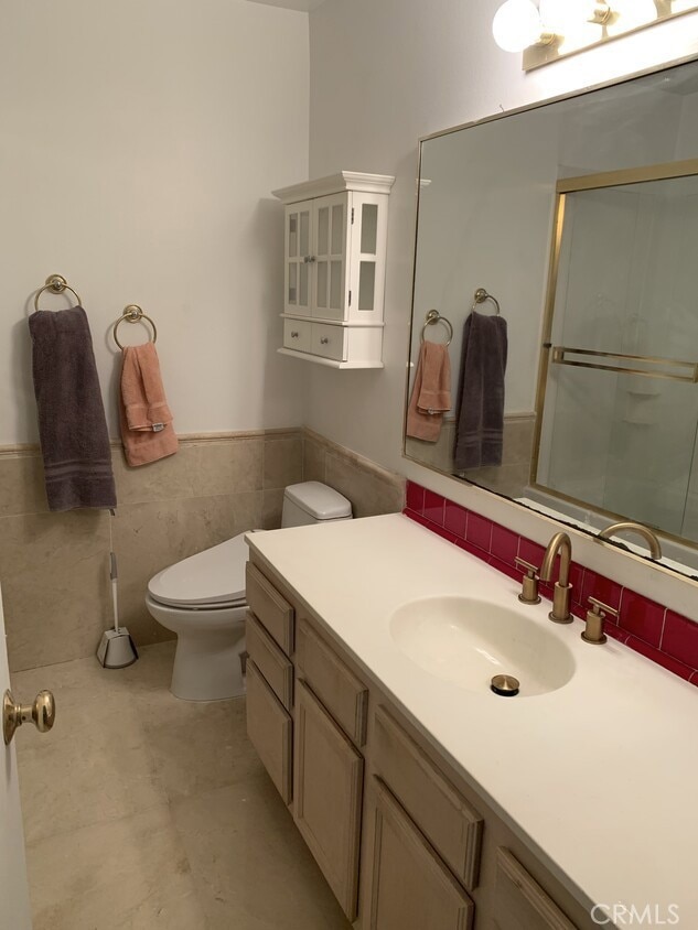 bathroom with vanity, an enclosed shower, tile walls, and toilet