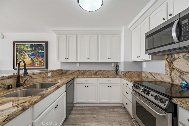 kitchen with sink, light hardwood / wood-style flooring, appliances with stainless steel finishes, white cabinetry, and dark stone counters