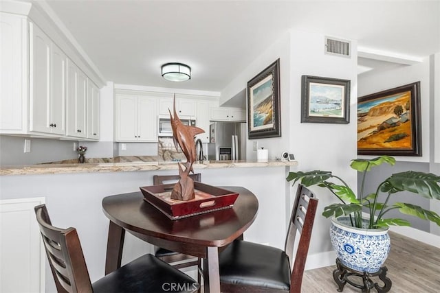 bar featuring sink, white cabinets, stainless steel appliances, light stone countertops, and light hardwood / wood-style flooring