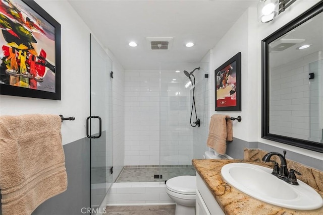 bathroom with vanity, toilet, and a shower with shower door