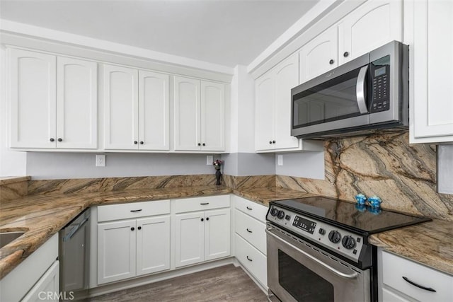 kitchen featuring appliances with stainless steel finishes, dark stone countertops, and white cabinets