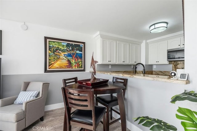 kitchen featuring hardwood / wood-style flooring, light stone countertops, sink, and white cabinets