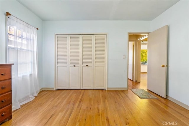 unfurnished bedroom with a closet, multiple windows, and light hardwood / wood-style flooring