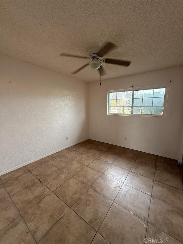 empty room with a textured ceiling, ceiling fan, and light tile patterned flooring