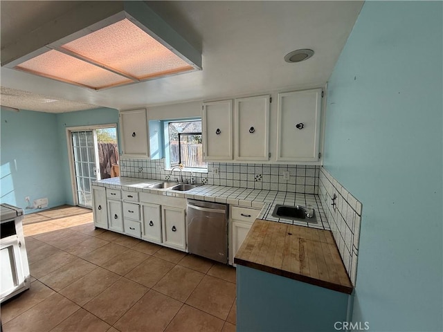 kitchen with appliances with stainless steel finishes, tasteful backsplash, sink, tile countertops, and white cabinetry