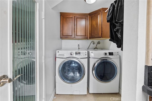 laundry room with light tile patterned flooring, cabinets, and washer and dryer