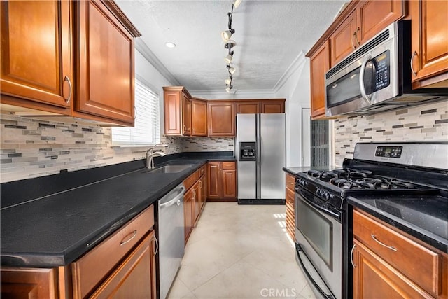 kitchen with rail lighting, appliances with stainless steel finishes, decorative backsplash, ornamental molding, and sink