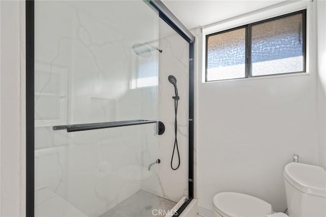 bathroom featuring toilet and a shower with shower door