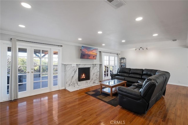 living room with hardwood / wood-style flooring, a healthy amount of sunlight, a premium fireplace, and ornamental molding