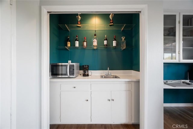 bar featuring hardwood / wood-style flooring, white cabinets, and sink