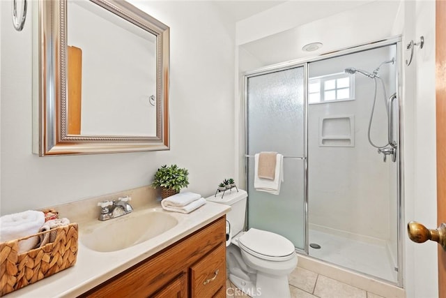 bathroom featuring tile patterned flooring, vanity, a shower with shower door, and toilet