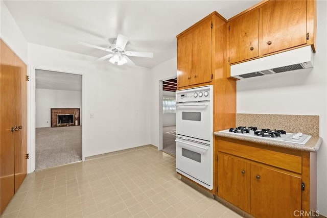 kitchen featuring ceiling fan, white appliances, and a brick fireplace