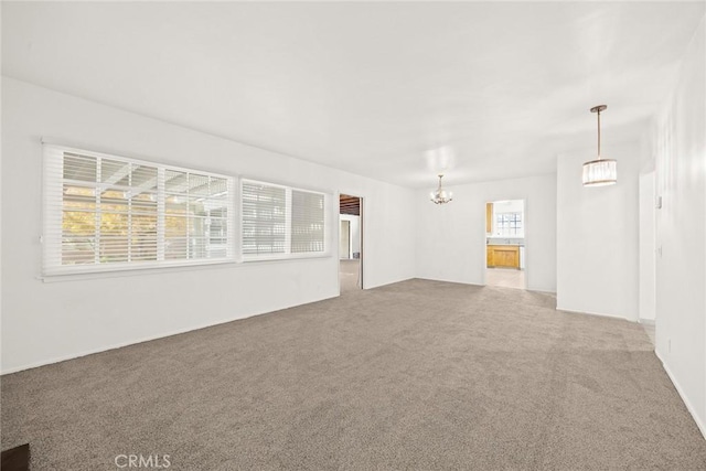 empty room featuring carpet flooring, a notable chandelier, and a wealth of natural light