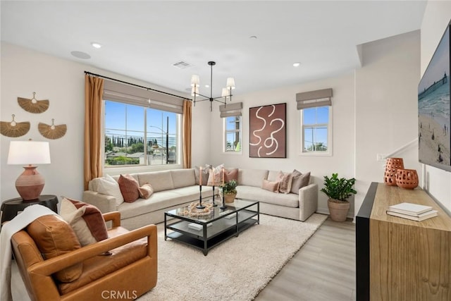 living room with plenty of natural light, a chandelier, and light hardwood / wood-style floors