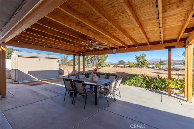 view of patio featuring a mountain view, ceiling fan, and a storage unit