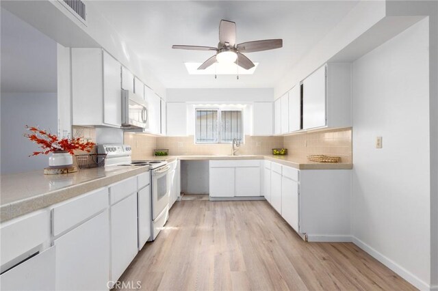 kitchen with sink, white cabinets, electric range, light hardwood / wood-style floors, and decorative backsplash