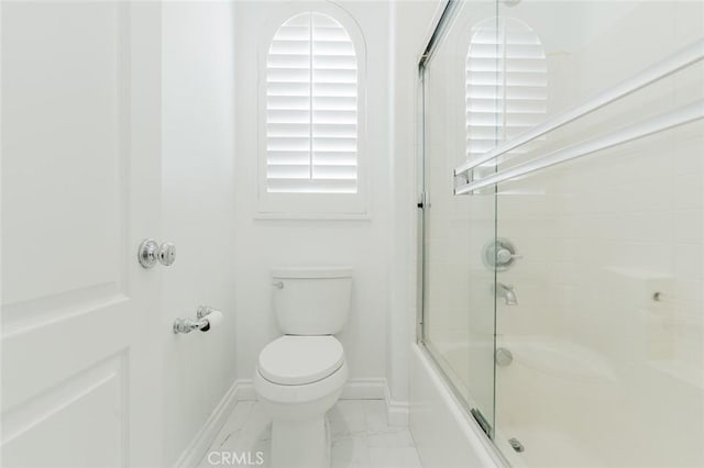 bathroom with toilet and combined bath / shower with glass door