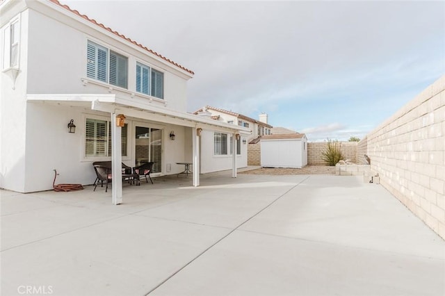 rear view of house with a storage shed and a patio