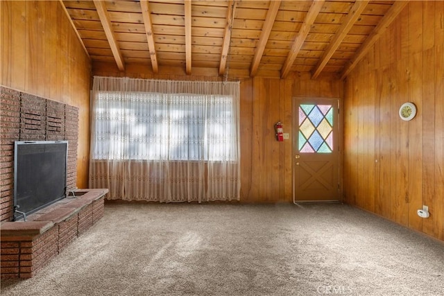 unfurnished living room with carpet flooring, vaulted ceiling with beams, wood ceiling, and wooden walls