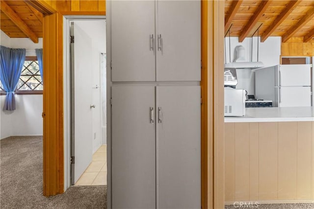 interior space with carpet, beamed ceiling, wooden ceiling, and white appliances