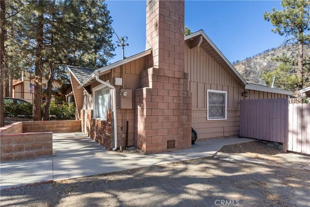 592 Mountain View Ave, Wrightwood, CA 92397 - view of property exterior featuring fence, a chimney, a patio, board and batten siding, and a mountain view