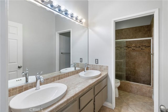 bathroom featuring toilet, vanity, tile patterned floors, and a shower with door