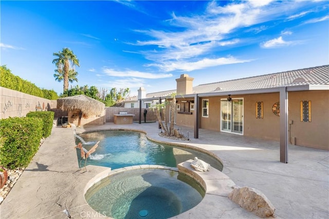 view of pool featuring pool water feature, ceiling fan, a patio area, and an in ground hot tub