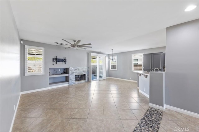 unfurnished living room with ceiling fan, light tile patterned flooring, and a healthy amount of sunlight