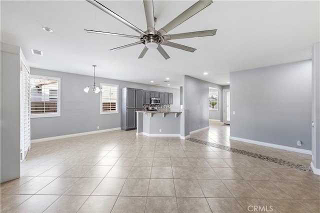 unfurnished living room with ceiling fan with notable chandelier and light tile patterned flooring