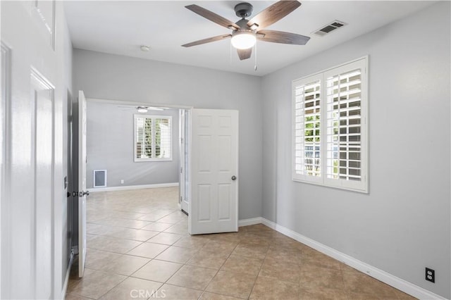 empty room with ceiling fan and light tile patterned floors