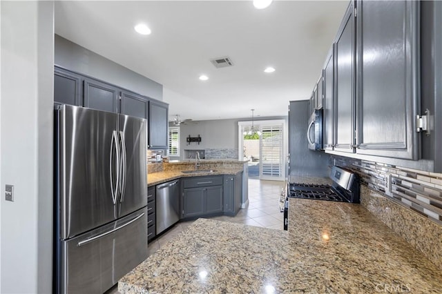 kitchen featuring ceiling fan, stone counters, hanging light fixtures, stainless steel appliances, and kitchen peninsula