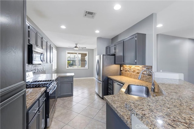 kitchen with sink, decorative backsplash, ceiling fan, light stone countertops, and stainless steel appliances