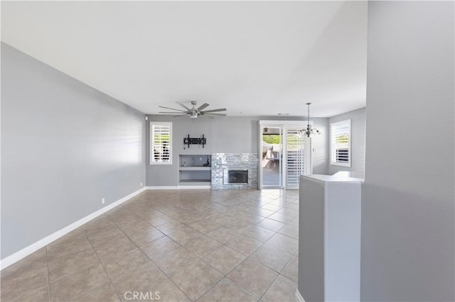 unfurnished living room featuring light tile patterned flooring, a healthy amount of sunlight, and ceiling fan with notable chandelier