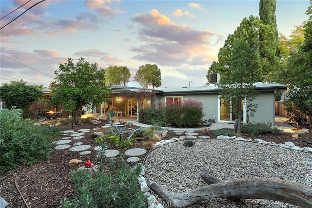 back house at dusk with a patio area and an outdoor fire pit