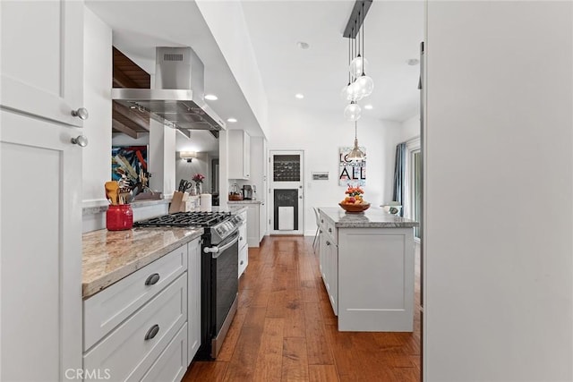 kitchen featuring white cabinets, pendant lighting, wall chimney range hood, and stainless steel gas range