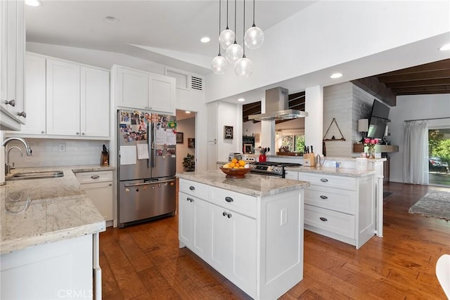 kitchen featuring a center island, wall chimney exhaust hood, stainless steel appliances, and vaulted ceiling