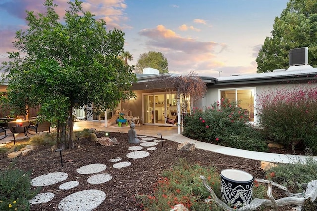 back house at dusk featuring a patio