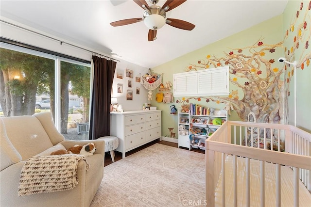 bedroom featuring lofted ceiling, ceiling fan, and a crib