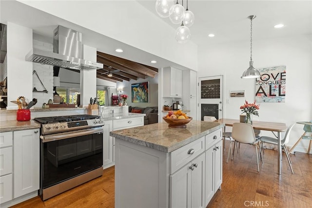 kitchen featuring wall chimney exhaust hood, light hardwood / wood-style floors, stainless steel range oven, and a kitchen island