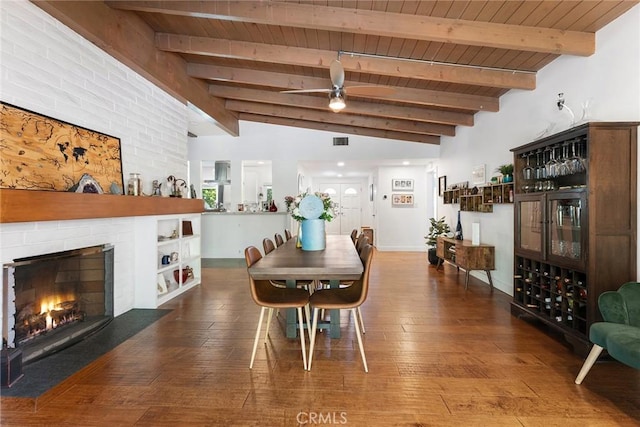 dining area with wooden ceiling, a brick fireplace, vaulted ceiling with beams, dark hardwood / wood-style floors, and ceiling fan